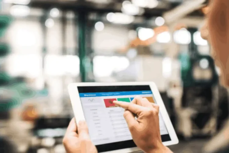 Worker using tablet to monitor tasks in factory with a manufacturing process automation app.