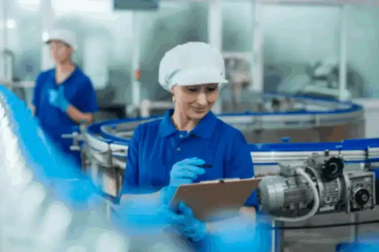 A factory worker monitors a conveyor belt, illustrating manufacturing process automation for efficiency.
