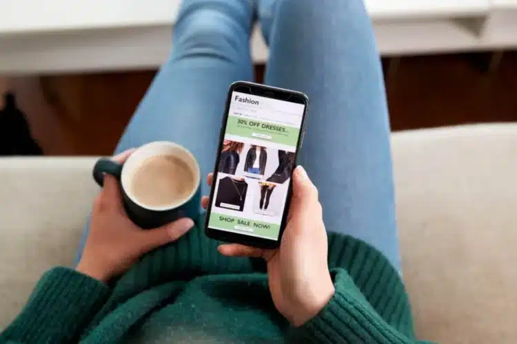A person holding a smartphone and browsing an online clothing store with discounts, representing the convenience of shopping through an Android eCommerce app.