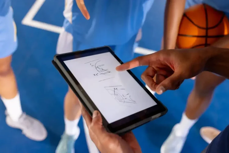 Coach using a tablet to show game strategy and player positions, highlighting the role of digital tools in modern sports management.