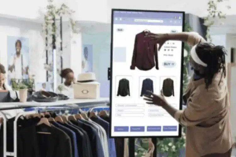 A shopper is interacting with a large digital display in a retail store, browsing clothing options, which represents Javascript retail app development.