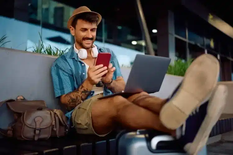 Traveler using a laptop and smartphone to manage bookings, showcasing the convenience of travel automation.