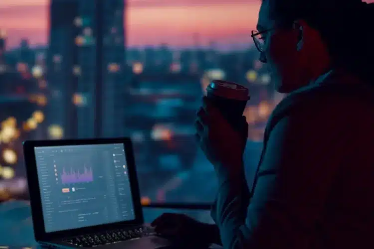 Professional analyzing property market data on a laptop with city skyline view, showcasing real estate analytics insights.