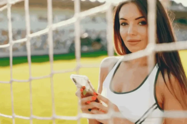 Woman at sports field using smartphone, showing features of a sports club fan engagement app.
