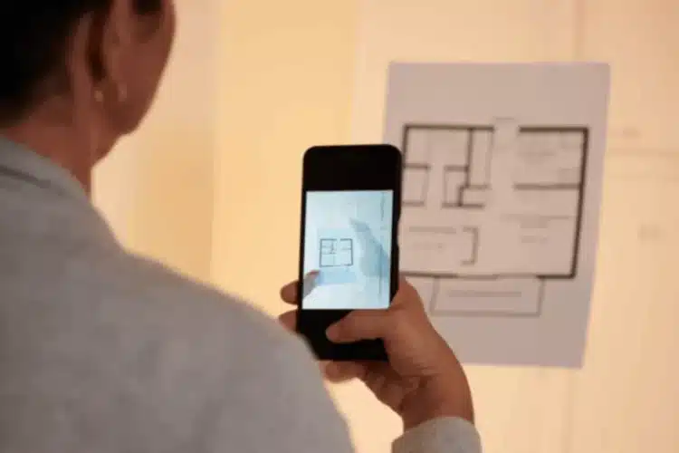 Person using smartphone to view floor plan, showing features of a real estate property search app.
