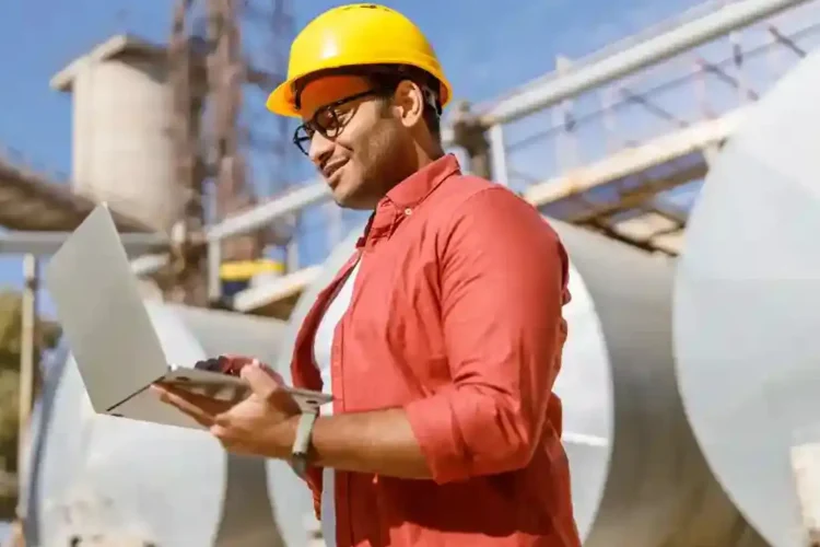 Engineer with laptop in industrial site using IoT for Predictive Maintenance and remote monitoring.