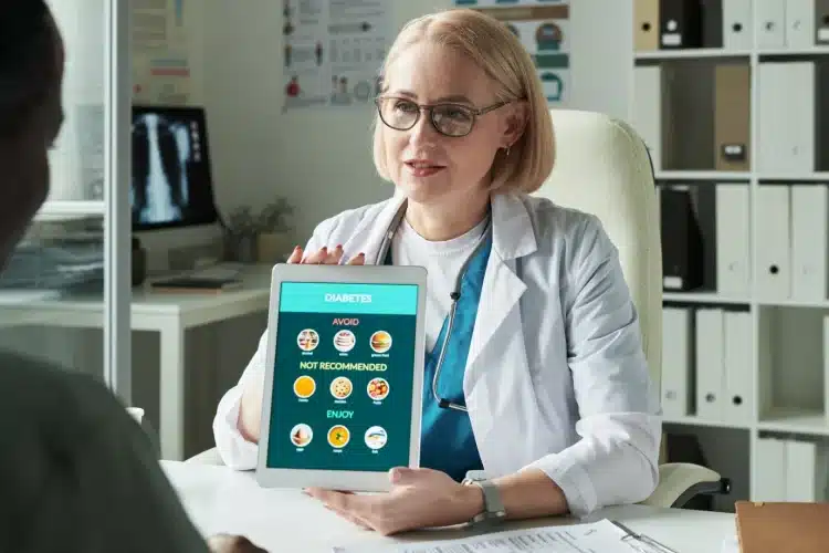 A doctor showing a digital tablet with diabetes diet guidelines to a patient, representing modern healthcare front-end development for improved patient engagement.