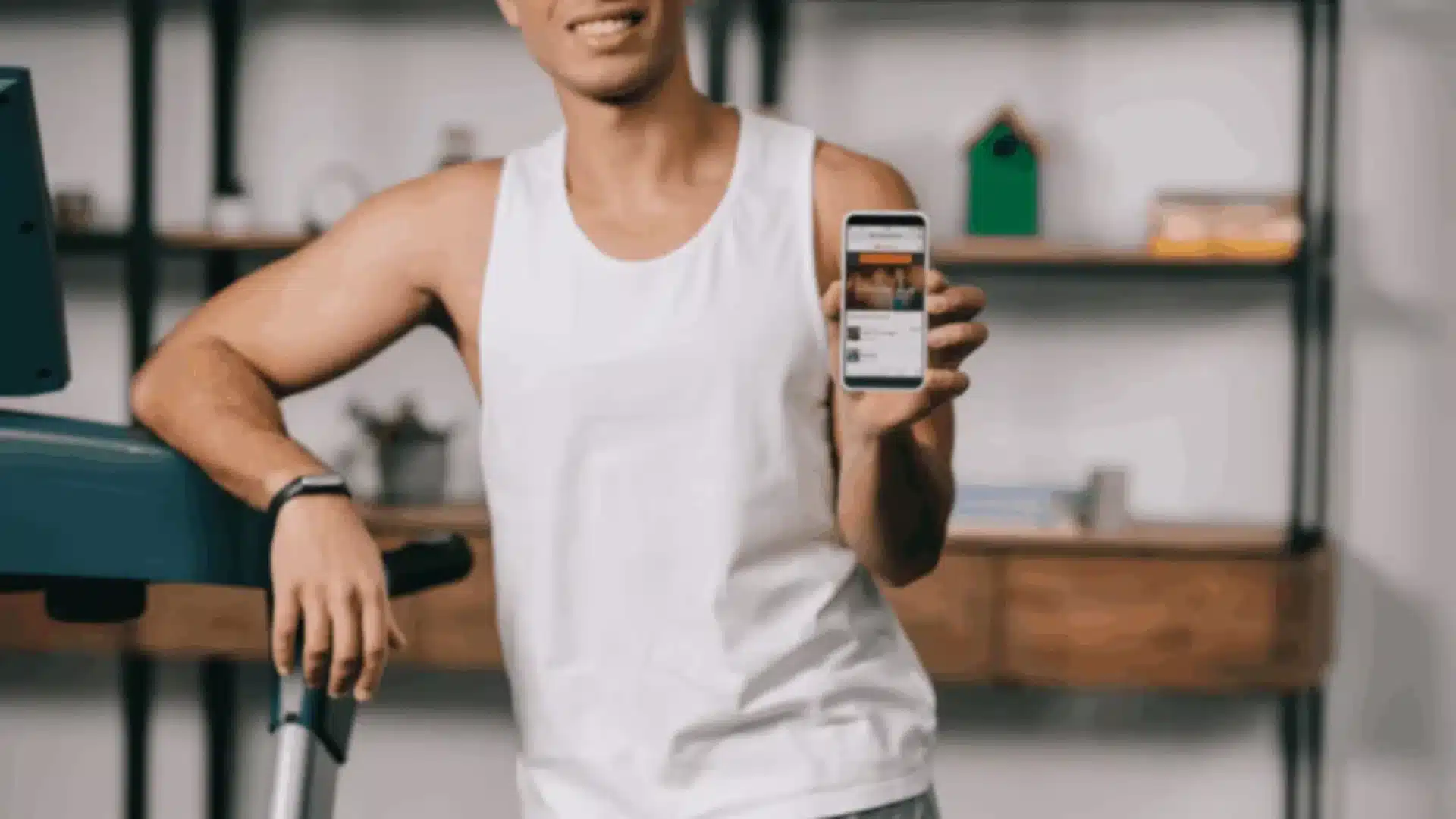 A smiling person in athletic wear holding up a smartphone displaying a fitness app, demonstrating the application of React Native in fitness app development.