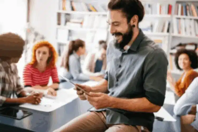 A diverse group of people engaged in a learning environment, with one person using a tablet, symbolizing React Native eLearning app development.