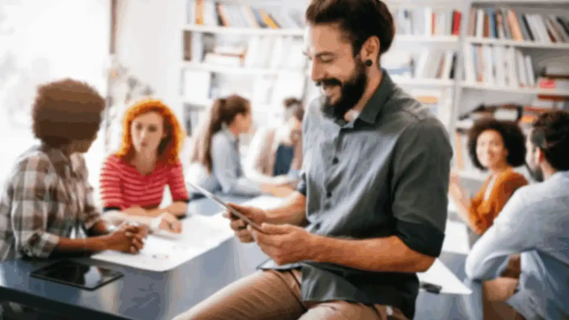 A diverse group of people engaged in a learning environment, with one person using a tablet, symbolizing React Native eLearning app development.