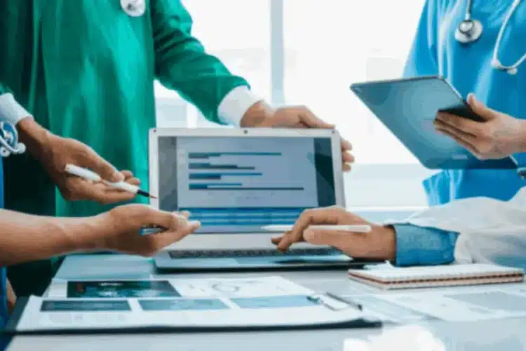 A group of healthcare professionals uses a laptop, showing a healthcare software modernization in patient care.