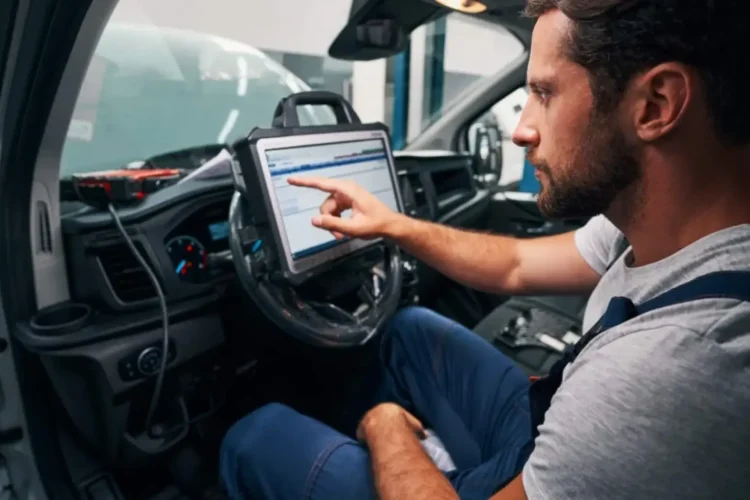 A mechanic uses a diagnostic tablet in a vehicle, demonstrating Custom Automotive Software Solutions.