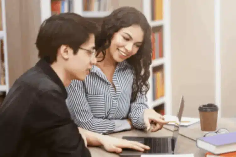 Two students collaborate on a laptop in a library, highlighting Effective Courseware Testing for success.