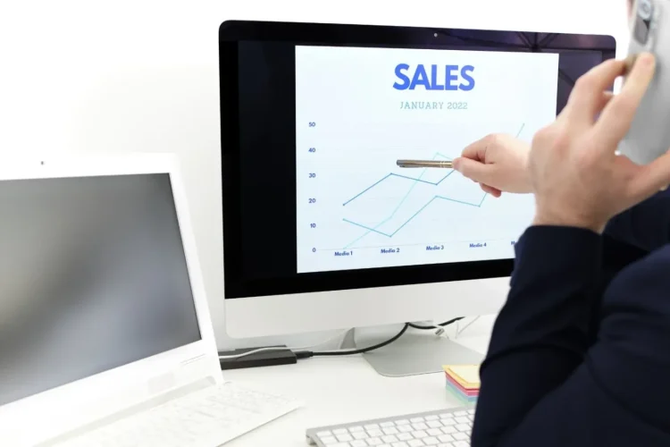 A businessman talks on the phone while analyzing a sales chart, a representation of eCommerce database development.