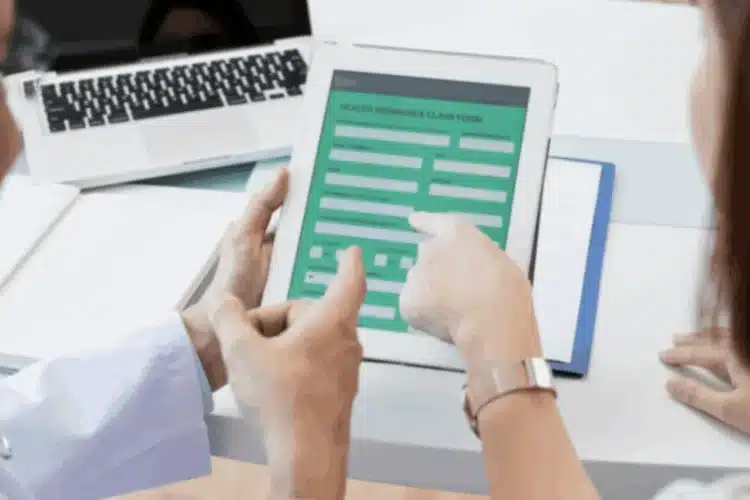 Healthcare professionals reviewing a digital health insurance claim form on a tablet for patient data management.