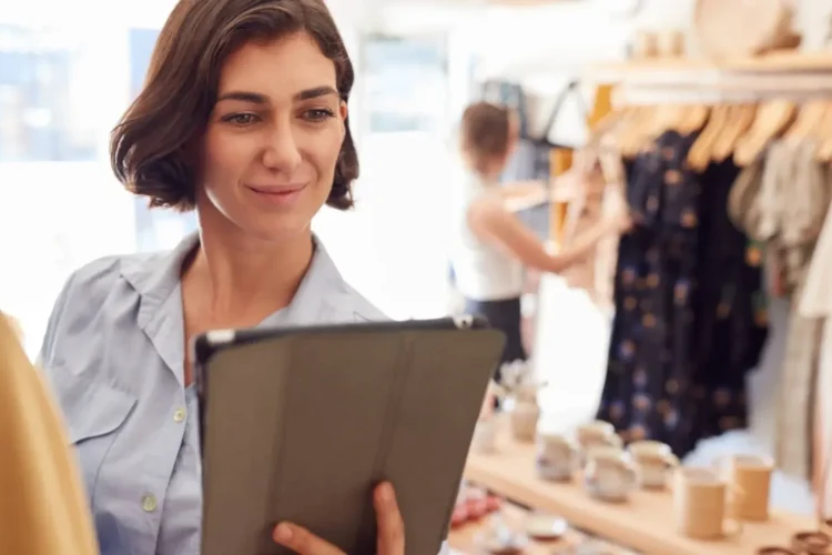 A smiling store owner uses a tablet, streamlining operations with Custom Retail Management Software.