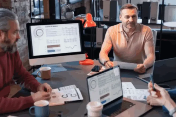 Digital campaign performance meeting: three professionals reviewing data on screens and papers.