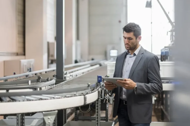 A supervisor in a warehouse uses a tablet, overseeing operations with Enterprise Resource Planning Software.