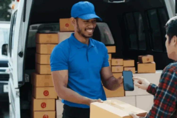 Delivery man using smartphone for package handover, showcasing benefits of logistics app development.