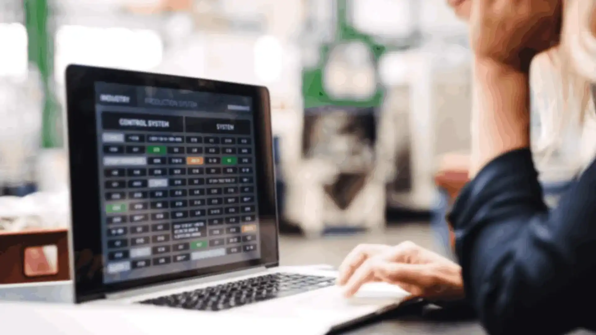 A worker uses a custom manufacturing app solution on a laptop in a factory setting.