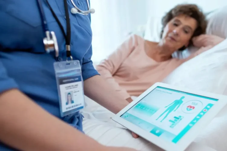 A nurse uses a tablet to check a patient's vitals, a product of Healthcare Software Development.